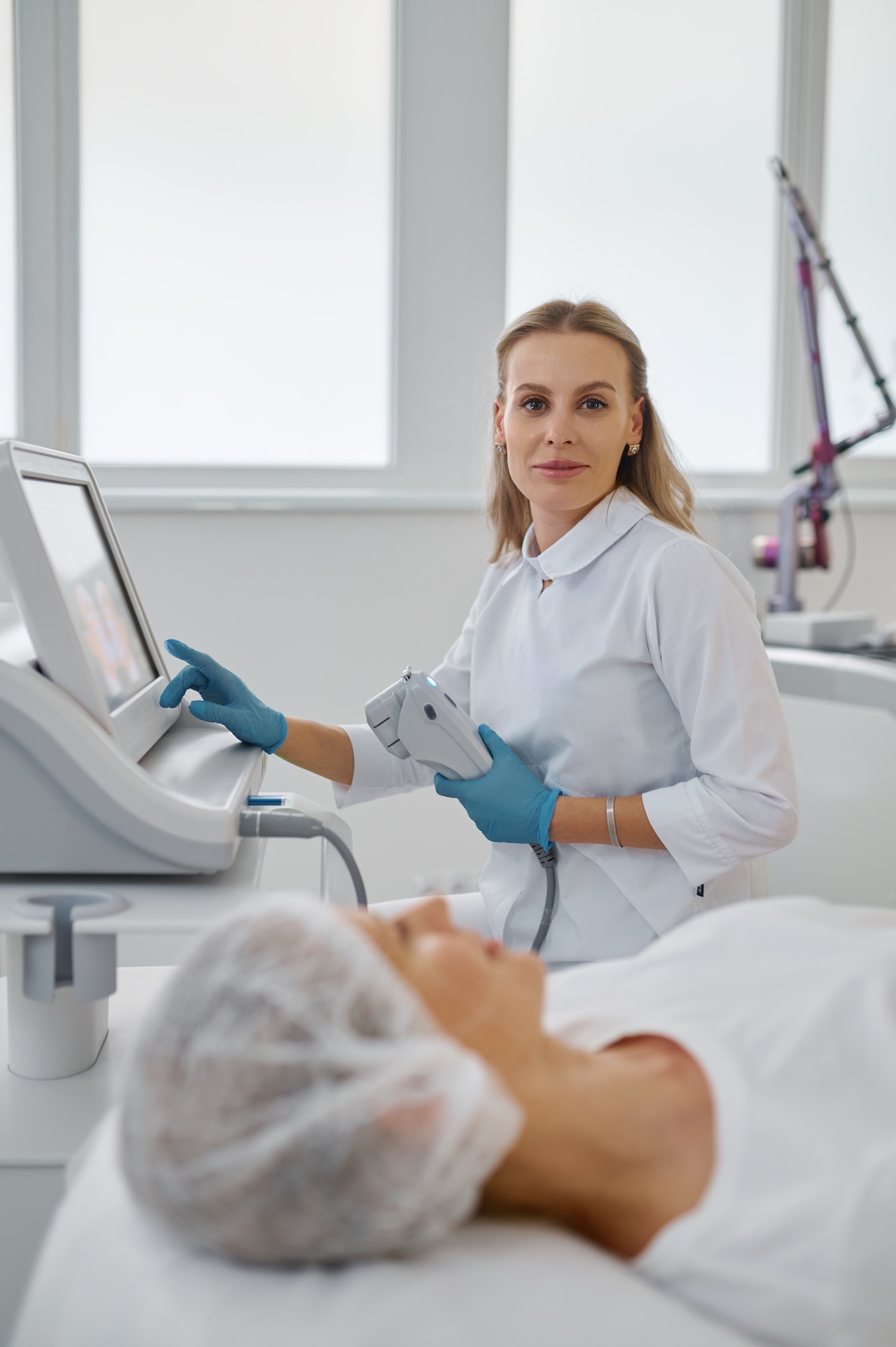 Portrait of female cosmetologist working with laser machine